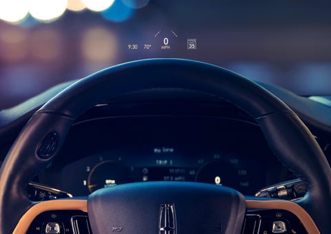 The available head-up display projects data on the windshield above the steering wheel inside a 2022 Lincoln Corsair as the driver navigates the city at night | Northgate Lincoln in Port Huron MI