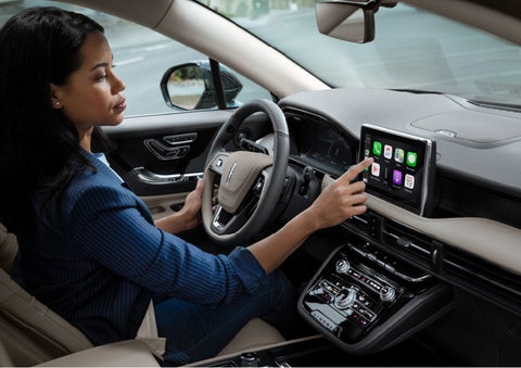 A woman in the driver’s seat of a 2022 Lincoln Corsair is touching the center digital screen to connect to Apple CarPlay<sup>®</sup> | Northgate Lincoln in Port Huron MI