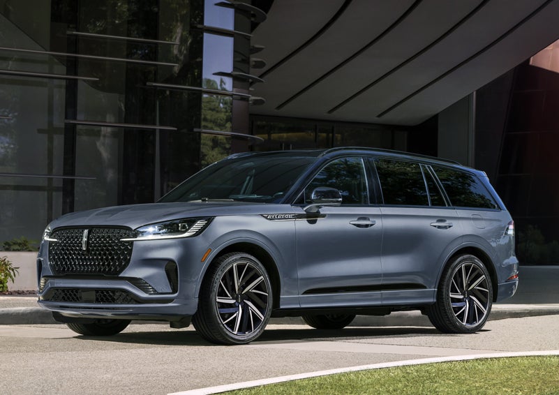 A gray 2025 Lincoln Aviator® SUV is parked outside a modern building showcasing the driver’s side of the vehicle. | Northgate Lincoln in Port Huron MI