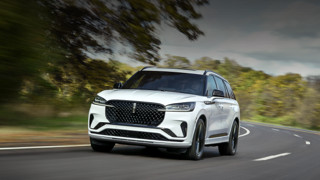 A white 2025 Lincoln Aviator® SUV is being driven down a road lined with trees. | Northgate Lincoln in Port Huron MI