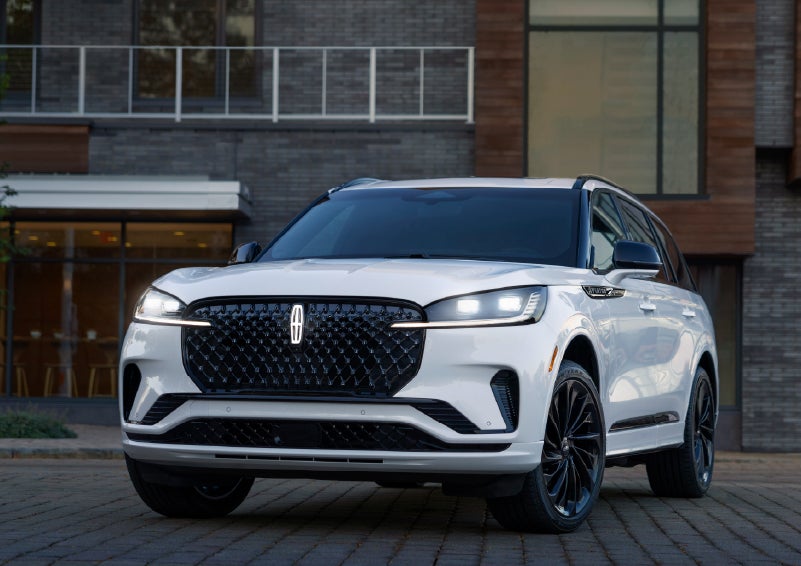 A 2026 Lincoln Aviator® Reserve model is shown with the available Jet Appearance Package parked near a restaurant. | Northgate Lincoln in Port Huron MI