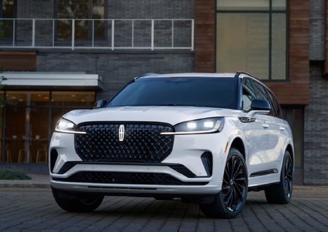A 2026 Lincoln Aviator® Reserve model is shown with the available Jet Appearance Package parked near a restaurant. | Northgate Lincoln in Port Huron MI