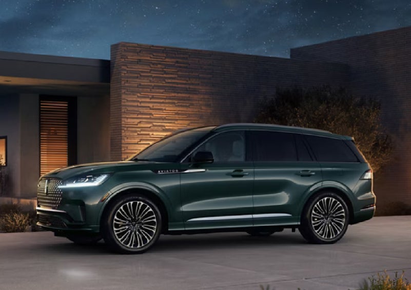 A green 2027 Lincoln Aviator® SUV is parked outside a contemporary home. | Northgate Lincoln in Port Huron MI