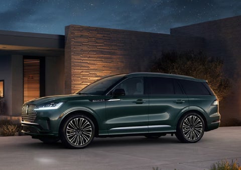 A green 2027 Lincoln Aviator® SUV is parked outside a contemporary home. | Northgate Lincoln in Port Huron MI