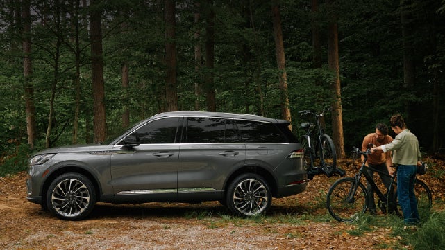 A father and son load e-bikes on a bike rack attached to a 2027 Lincoln Aviator® SUV. | Northgate Lincoln in Port Huron MI